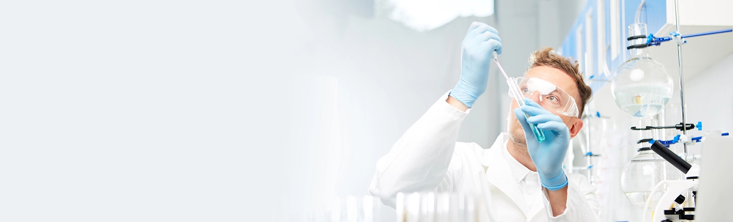 Scientist using pipette in lab with glassware and equipment.