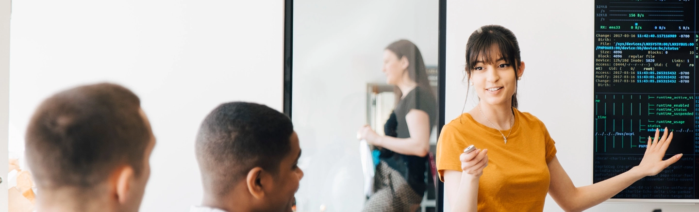 Woman presenting code and data charts to team inside an office.