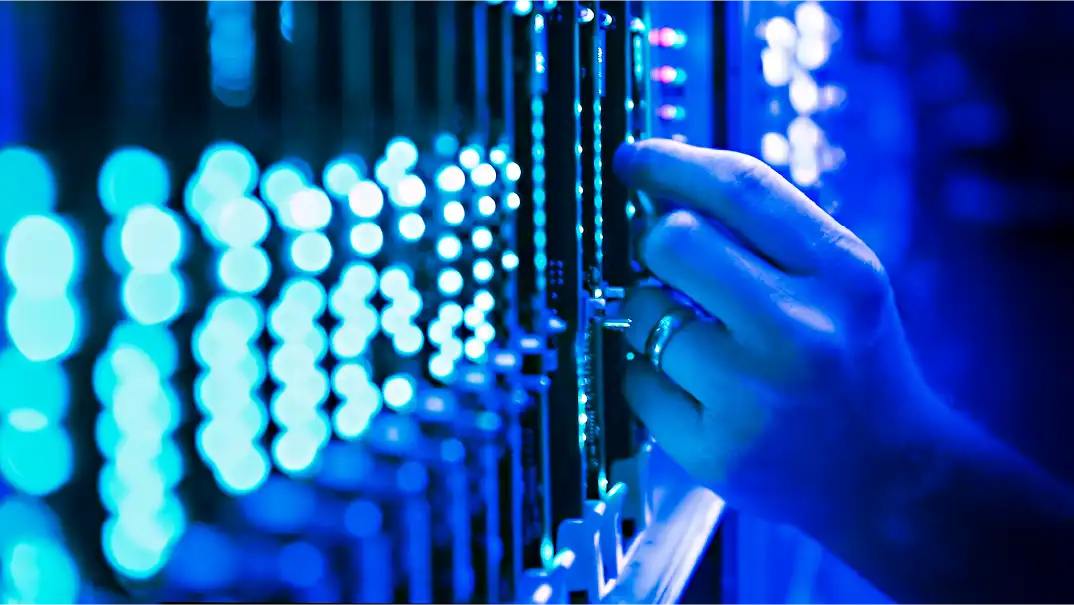 Hand interacting with server rack under blue lighting.