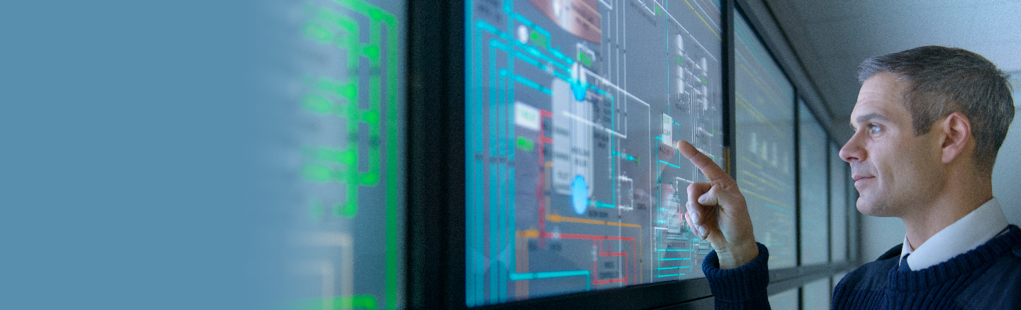 A man in a blue sweater points to a clear screen that has multiple colored lines.